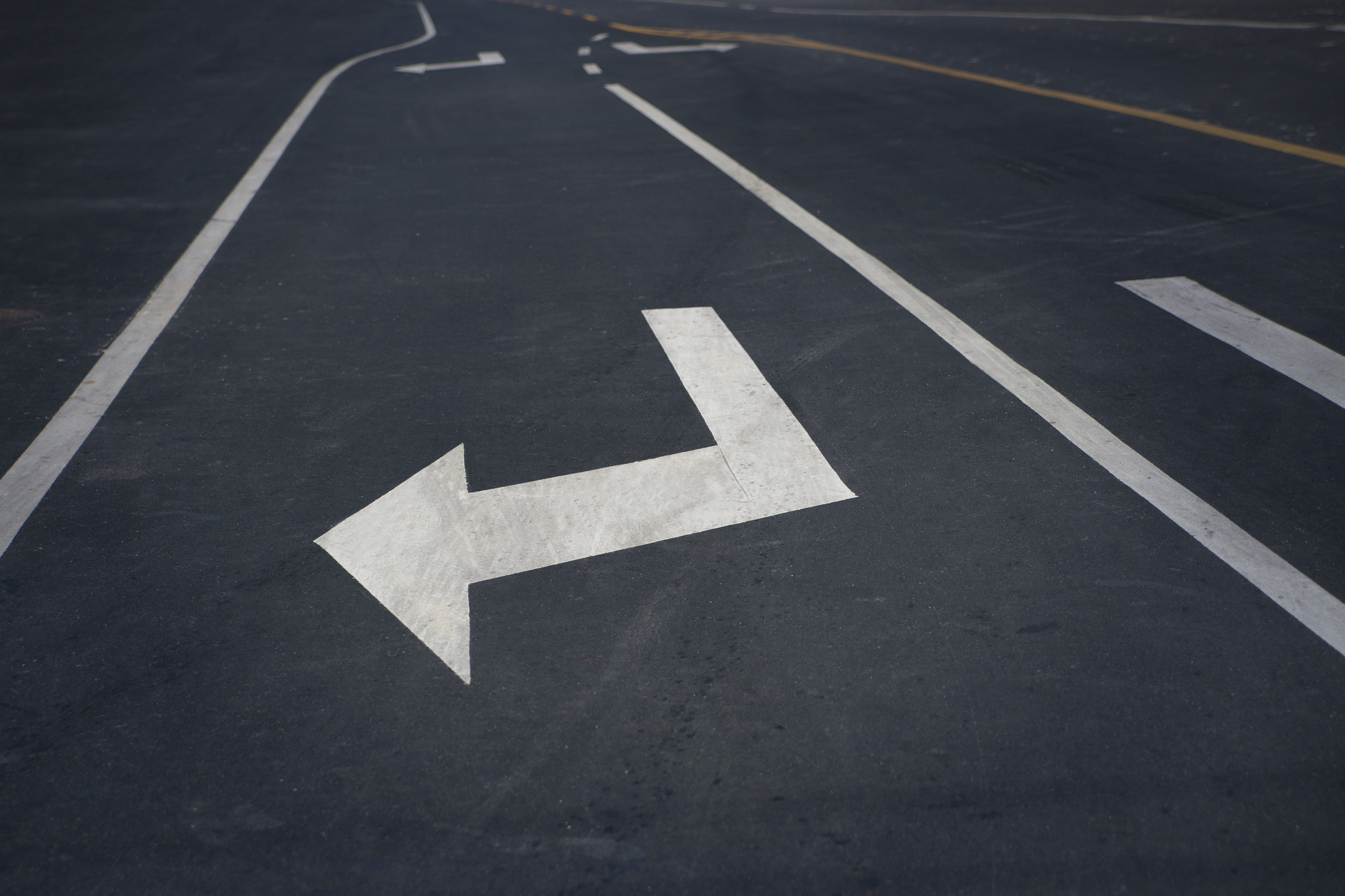 Flèche blanche sur route indiquant gauche.