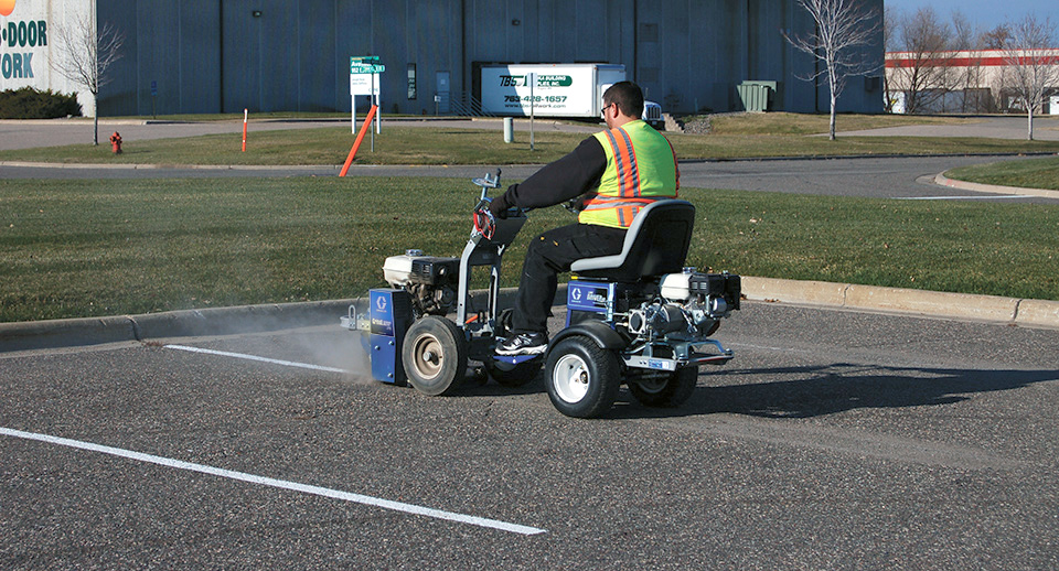 Homme peint des lignes de parking avec une machine.